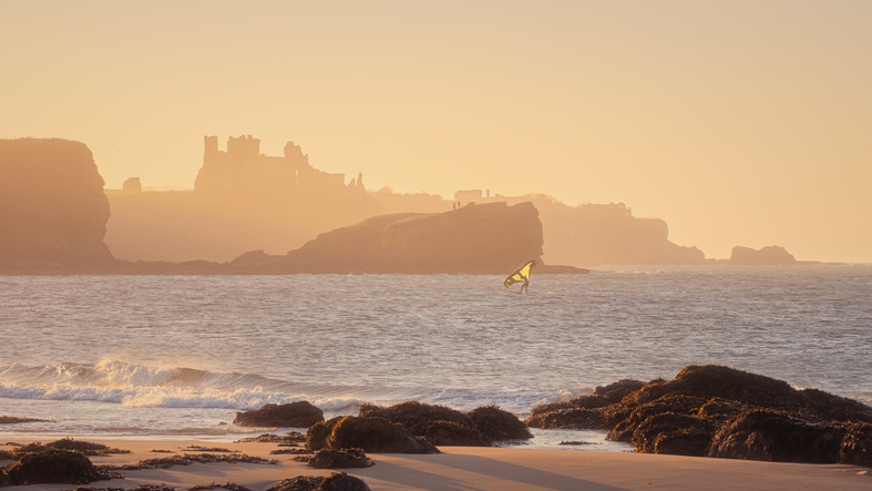 Windsurfer at sunny windy day against the backdrop of coastal cliffs