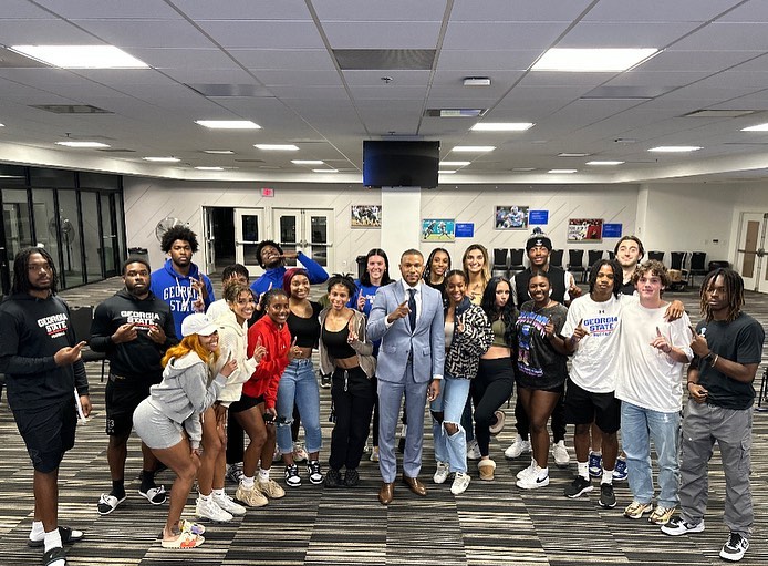 Dr. Marcus Bright poses with students during a recent speech.