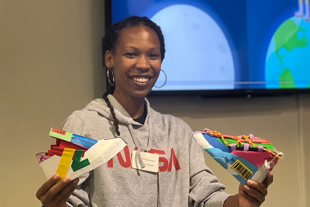 Sabrina Thompson holding prototype sneakers made by STEMulating Art students. Nice Kicks