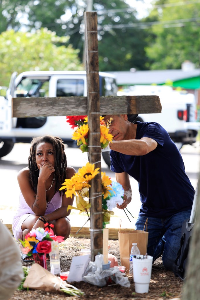 A woman who goes by the name of "Queen" pays her respects to the victims of Saturday's shooting next to artist Roberto Marquez, of Dallas, Monday, Aug. 28, 2023, near the site of the attack at a Dollar General store in Jacksonville, Fla. Queen says she is a manager at the store and was holed up in the office at the store when the shooting occurred. 