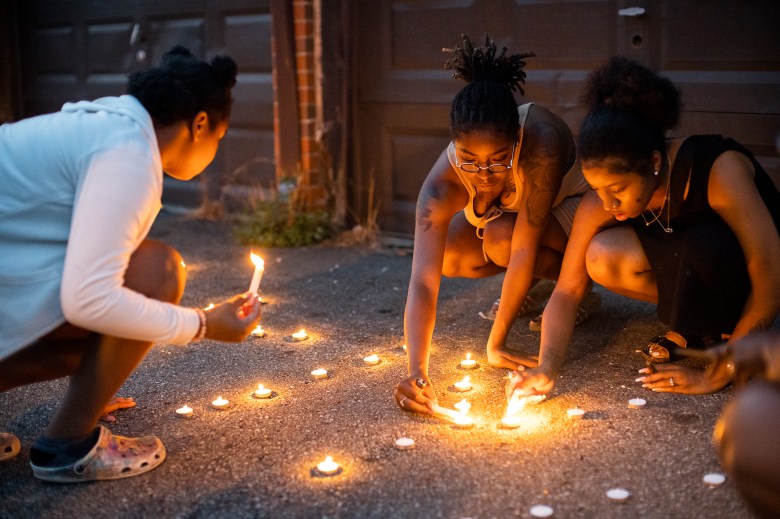 Sandriana McBroom, right, and Makhiya Mcbroom, center, light candles that spell out "RIP Kiya" at a vigil.