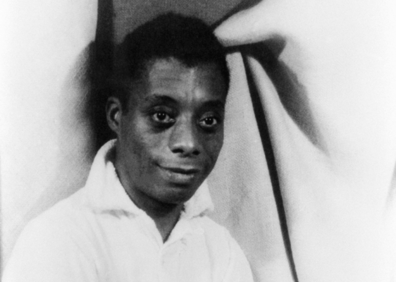 Portait of James Baldwin seated.