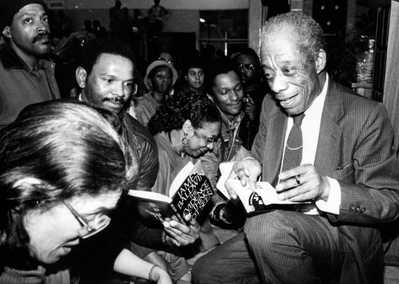 James Baldwin signing books in a crowded bookstore.