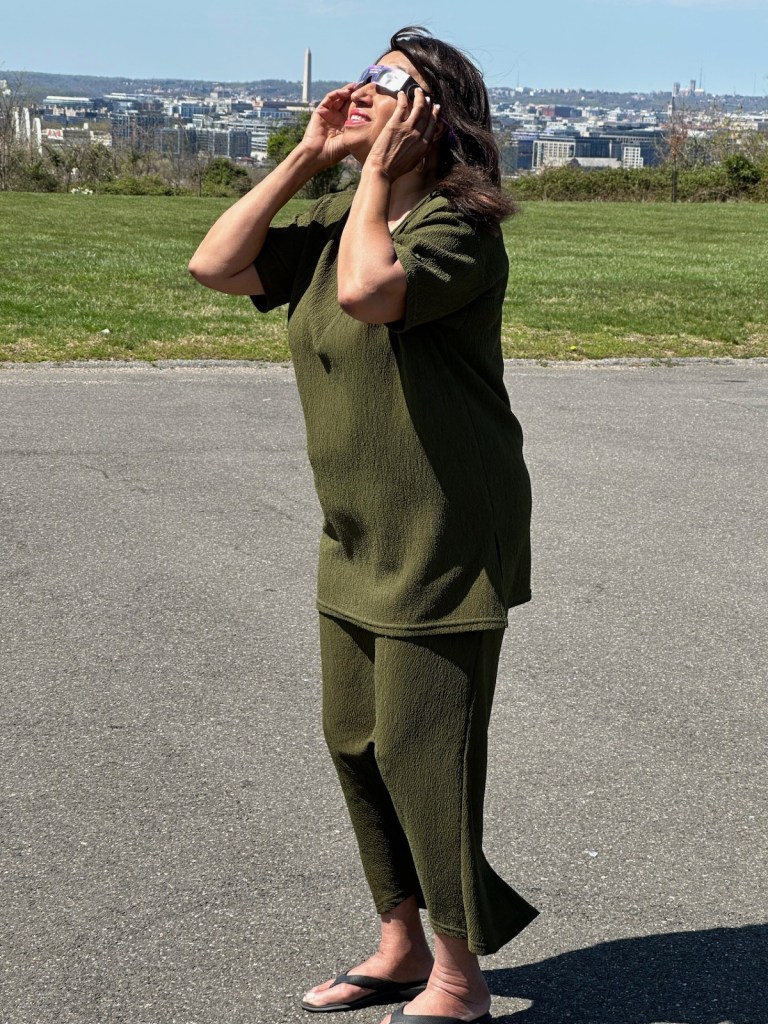 Julie Rone stands outside Our Lady of Perpetual Help Catholic Church in Southeast D.C. to view a rare solar eclipse on April 8. (D.R. Barnes/The Washington Informer)