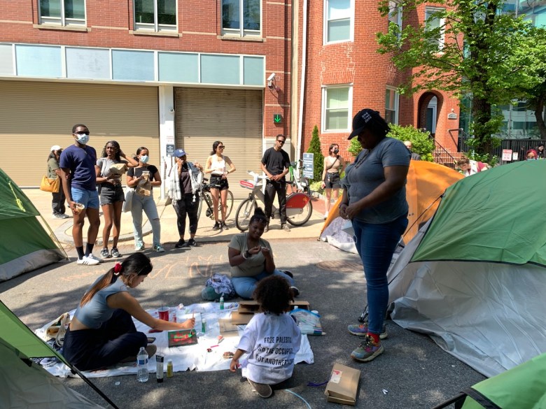 A toddler paints with other protesters, while the child’s mom watches, on April 28. (Kayla Benjamin/The Washington Informer)